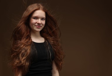 Photo of Portrait of beautiful teenage girl with healthy wavy hair on brown background. Space for text