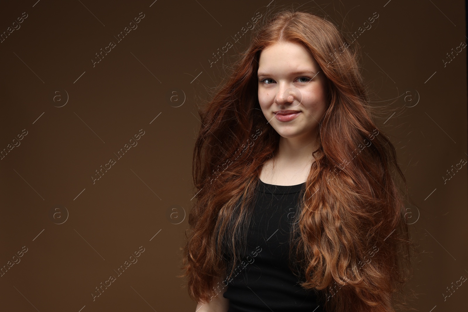 Portrait of beautiful teenage girl with healthy wavy hair on brown background. Space for text Photo of Portrait of beautiful teenage girl with healthy wavy hair on brown background. Space for text