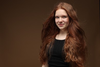 Photo of Portrait of beautiful teenage girl with healthy wavy hair on brown background. Space for text