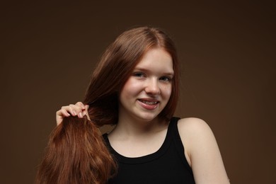 Photo of Portrait of smiling teenage girl with healthy wavy hair on brown background