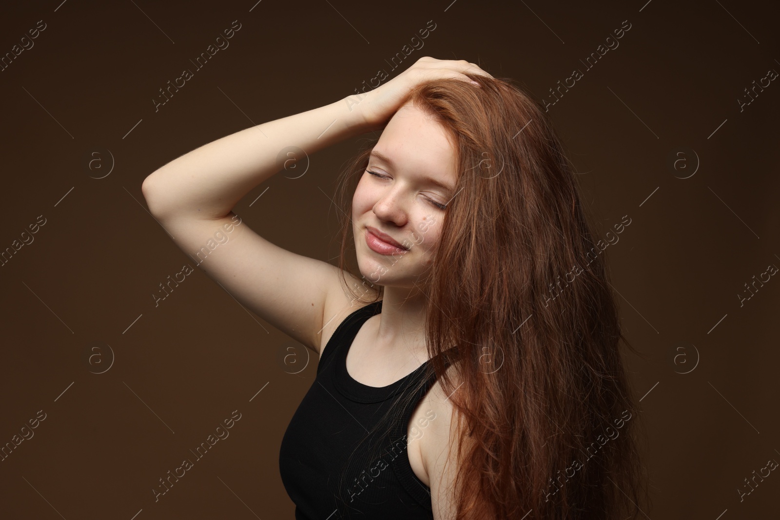 Beautiful teenage girl with healthy wavy hair on brown background Photo of Beautiful teenage girl with healthy wavy hair on brown background
