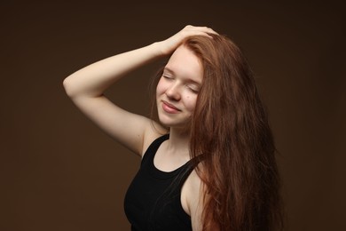 Photo of Beautiful teenage girl with healthy wavy hair on brown background