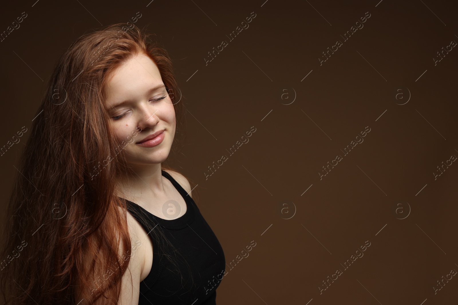 Beautiful teenage girl with healthy wavy hair on brown background. Space for text Photo of Beautiful teenage girl with healthy wavy hair on brown background. Space for text