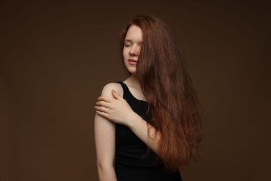 Photo of Beautiful teenage girl with healthy wavy hair on brown background