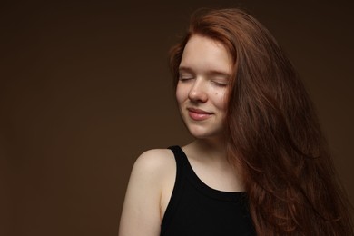 Photo of Beautiful teenage girl with healthy wavy hair on brown background. Space for text