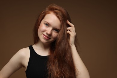 Photo of Portrait of beautiful teenage girl with healthy wavy hair on brown background