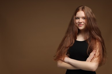 Photo of Portrait of beautiful teenage girl with healthy wavy hair on brown background. Space for text