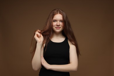 Photo of Portrait of beautiful teenage girl with healthy wavy hair on brown background