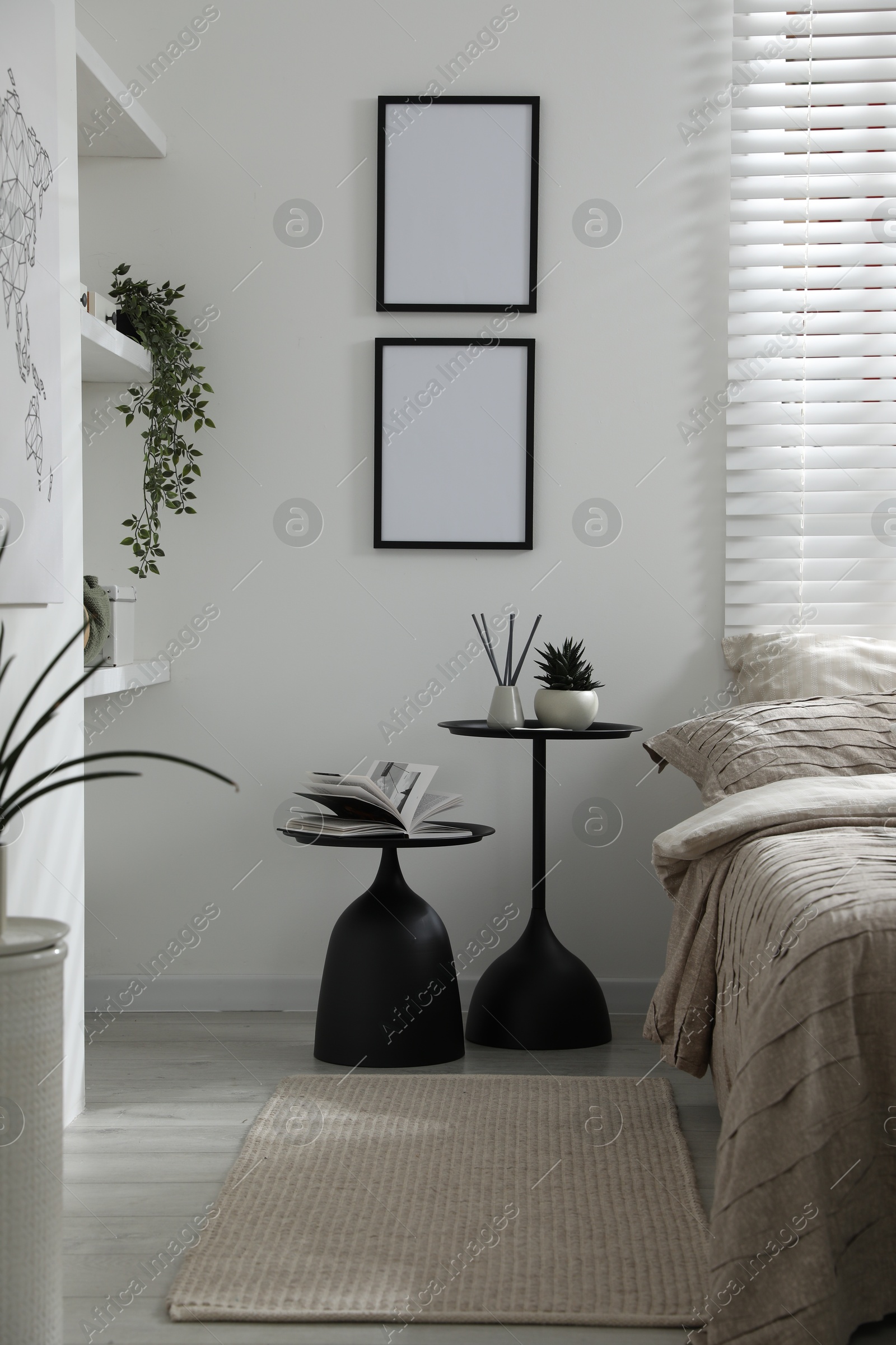 Photo of Comfortable bed with beautiful linens, nesting tables and decor in bedroom