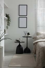 Photo of Comfortable bed with beautiful linens, nesting tables and decor in bedroom
