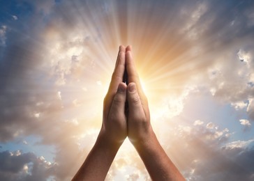 Image of Man praying against beautiful sky with sun, closeup