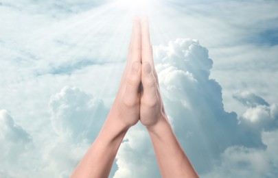 Image of Woman praying against beautiful sky with sun, closeup