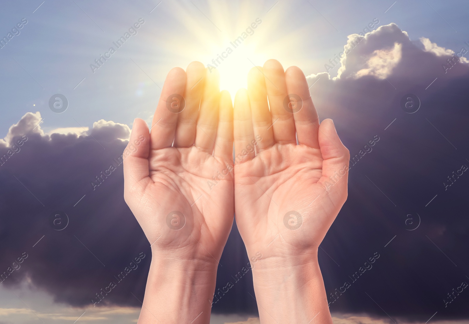 Woman praying against beautiful sky with sun, closeup Image of Woman praying against beautiful sky with sun, closeup