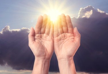 Image of Woman praying against beautiful sky with sun, closeup