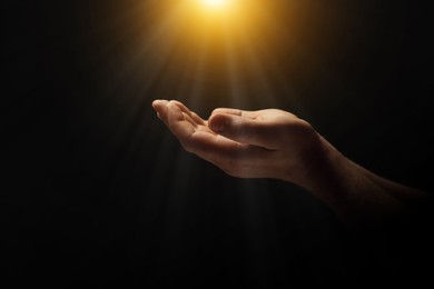 Image of Man illuminated by holy light praying in darkness, closeup