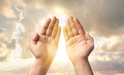 Image of Man praying against beautiful sky with sun, closeup