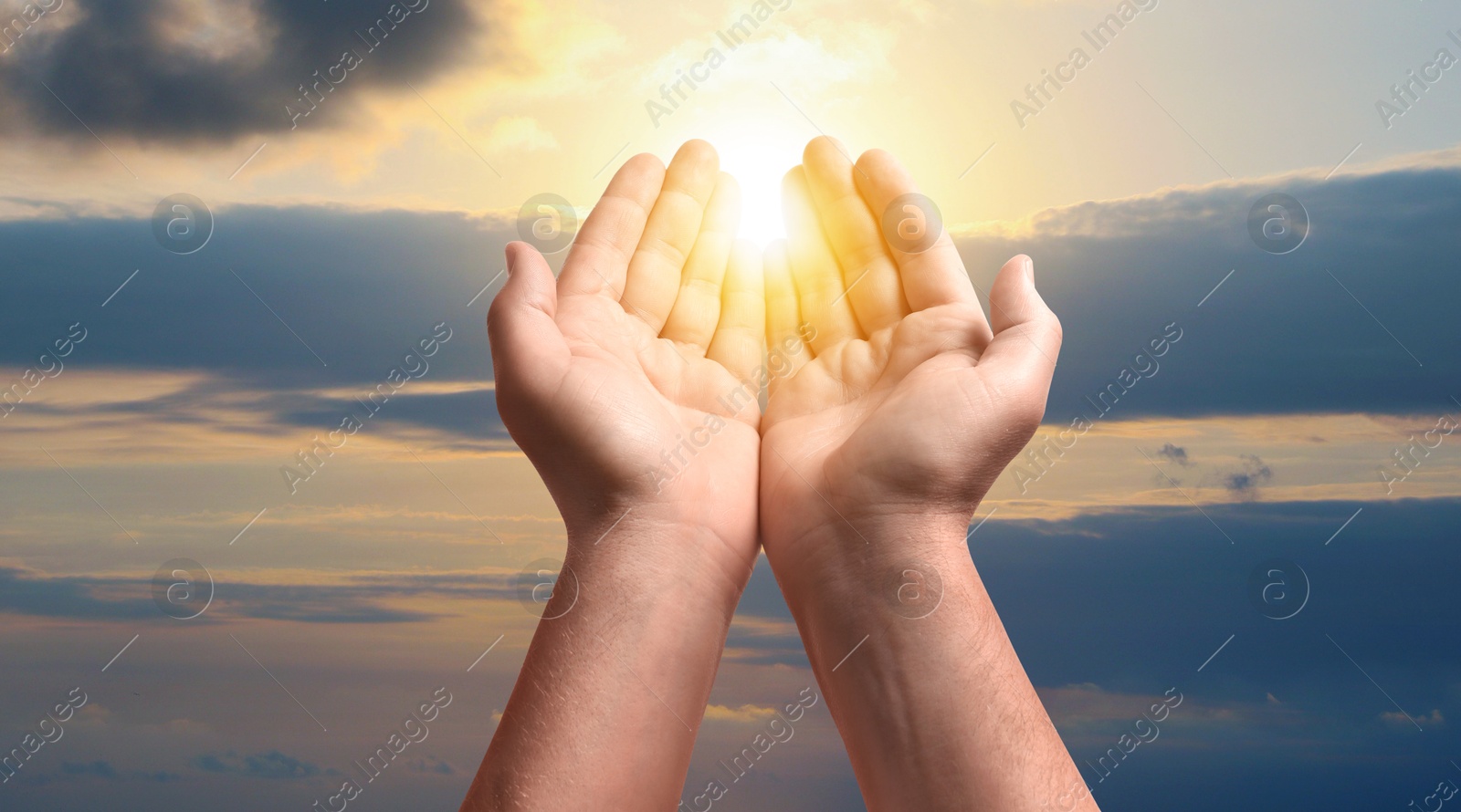 Man praying against beautiful sky with sun, closeup Image of Man praying against beautiful sky with sun, closeup