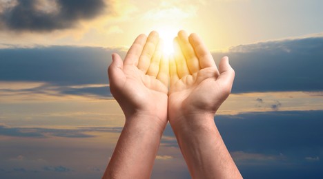 Image of Man praying against beautiful sky with sun, closeup