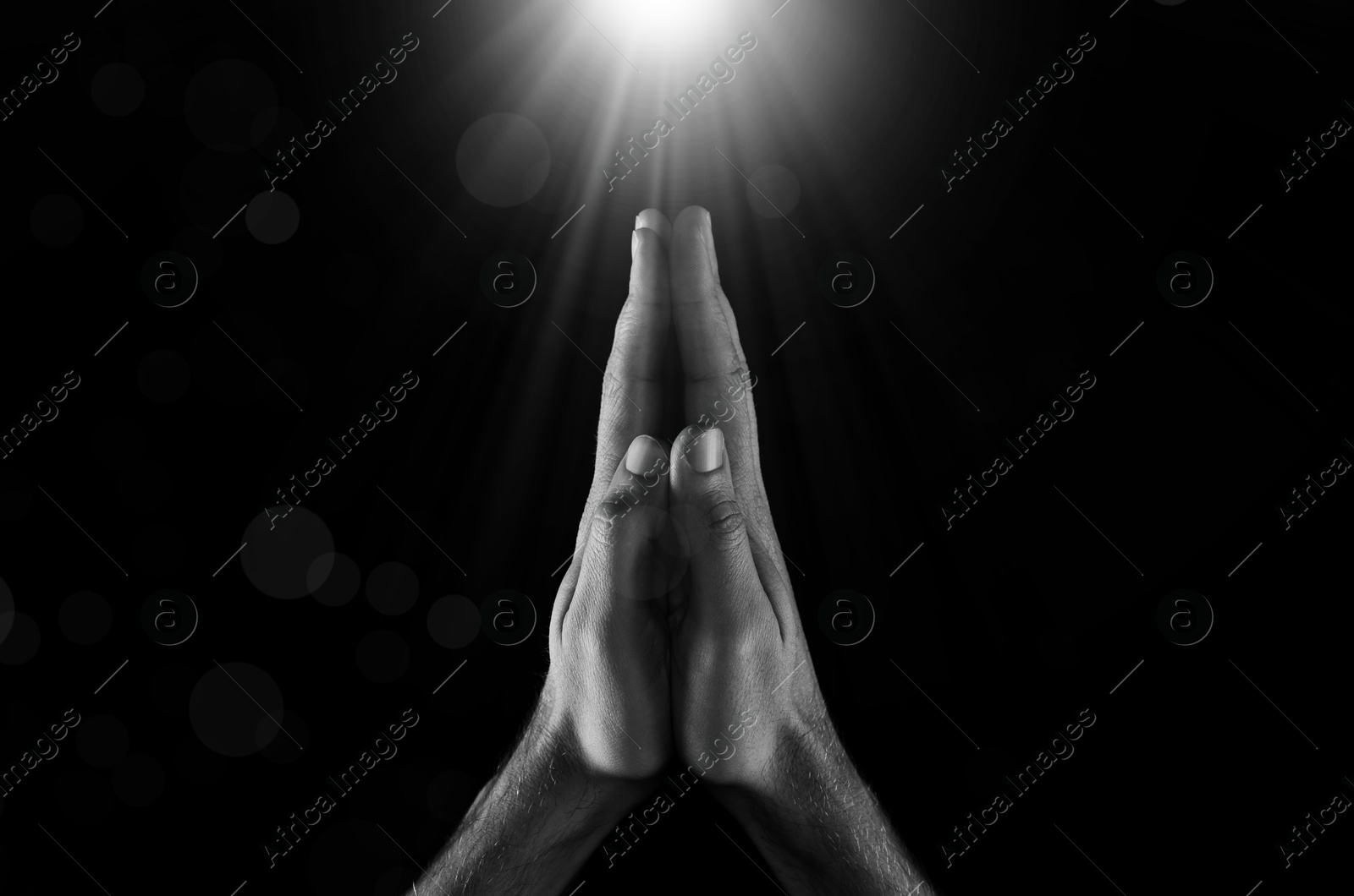 Man illuminated by holy light praying in darkness, closeup. Black-and-white effect Image of Man illuminated by holy light praying in darkness, closeup. Black-and-white effect