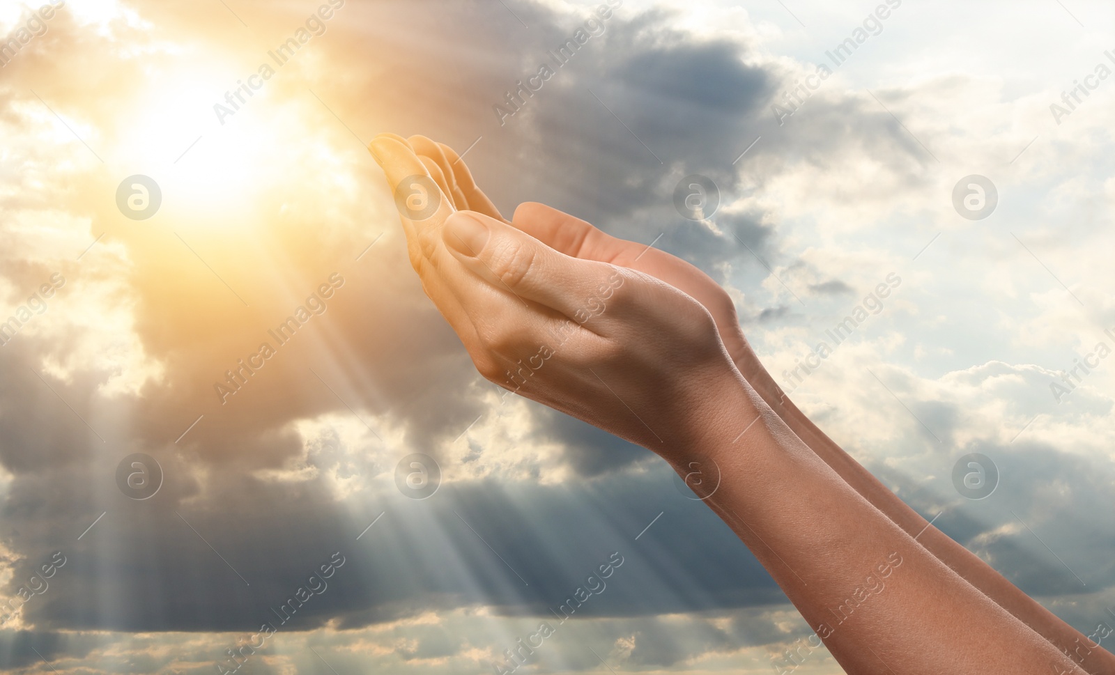 Woman praying against beautiful sky with sun, closeup Image of Woman praying against beautiful sky with sun, closeup