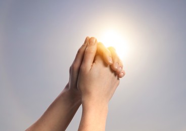 Image of Woman praying against beautiful sky with sun, closeup