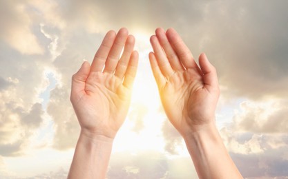 Image of Woman praying against beautiful sky with sun, closeup