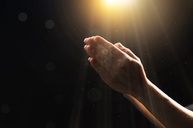 Image of Woman illuminated by holy light praying in darkness, closeup