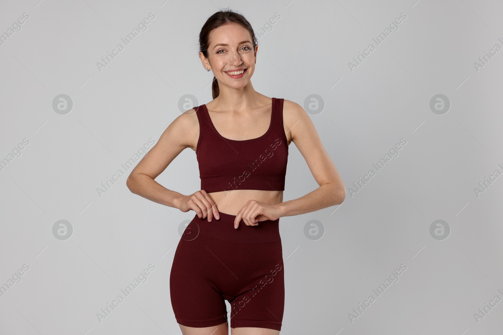Beautiful woman with flat belly on gray background Photo of Beautiful woman with flat belly on gray background