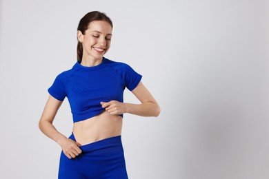 Photo of Beautiful woman with flat belly on gray background, space for text