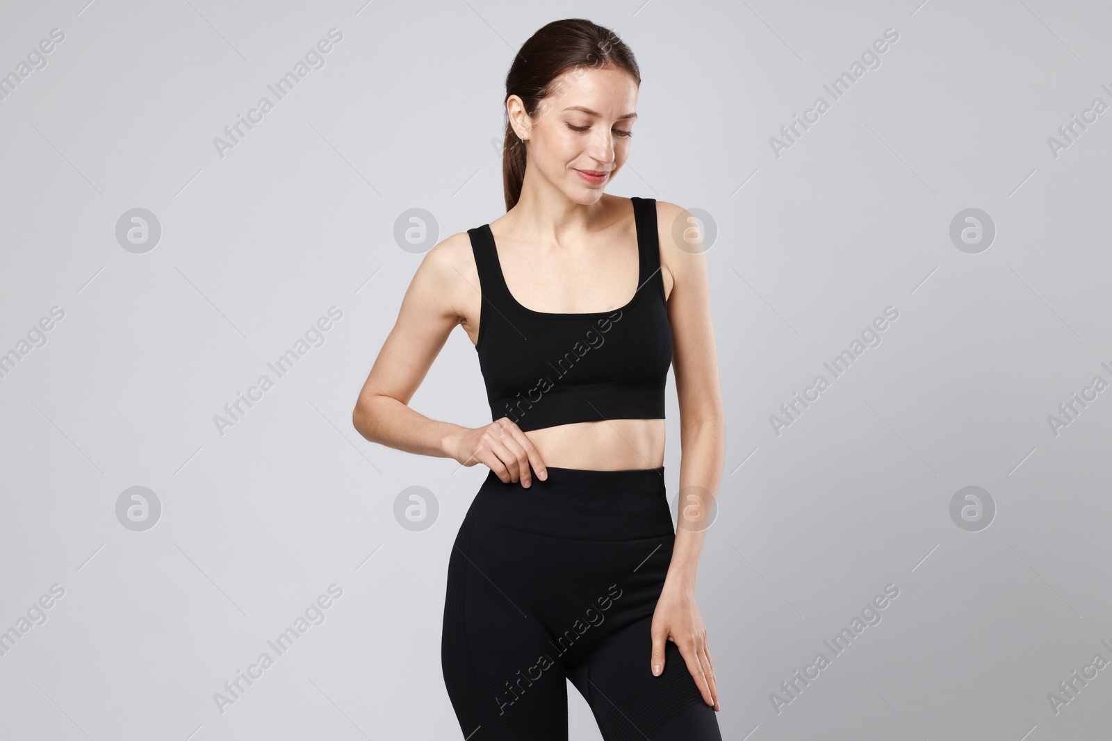 Beautiful woman with flat belly on gray background Photo of Beautiful woman with flat belly on gray background