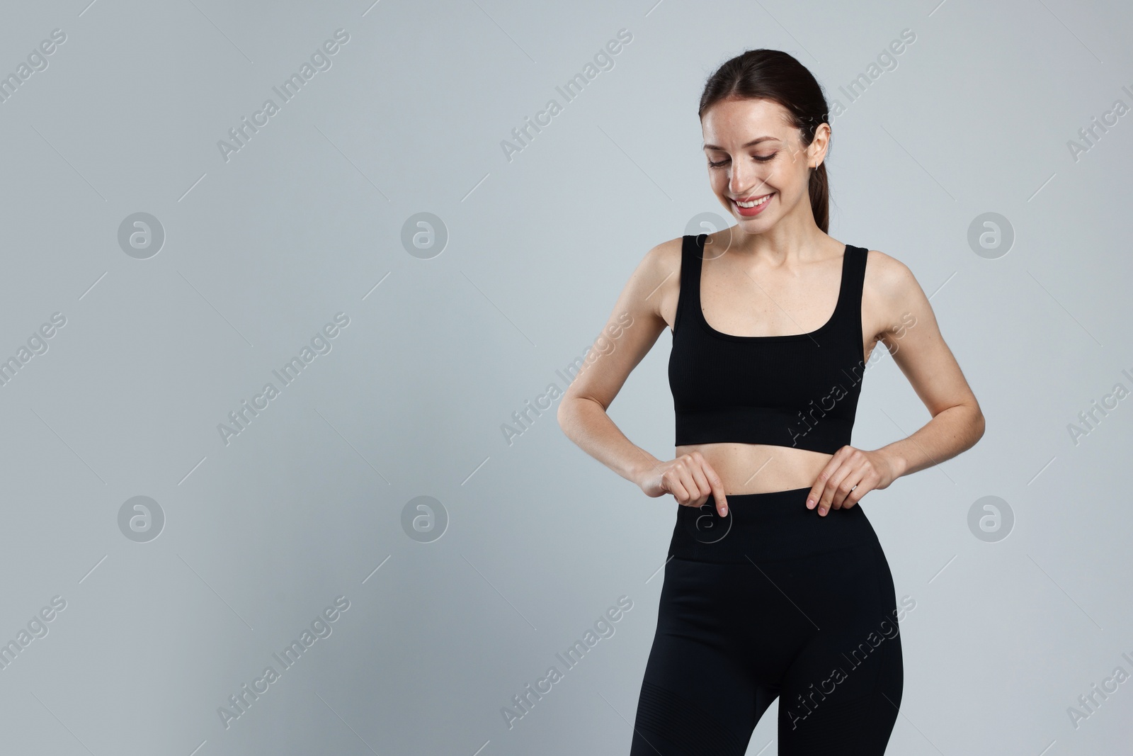 Beautiful woman with flat belly on gray background, space for text Photo of Beautiful woman with flat belly on gray background, space for text