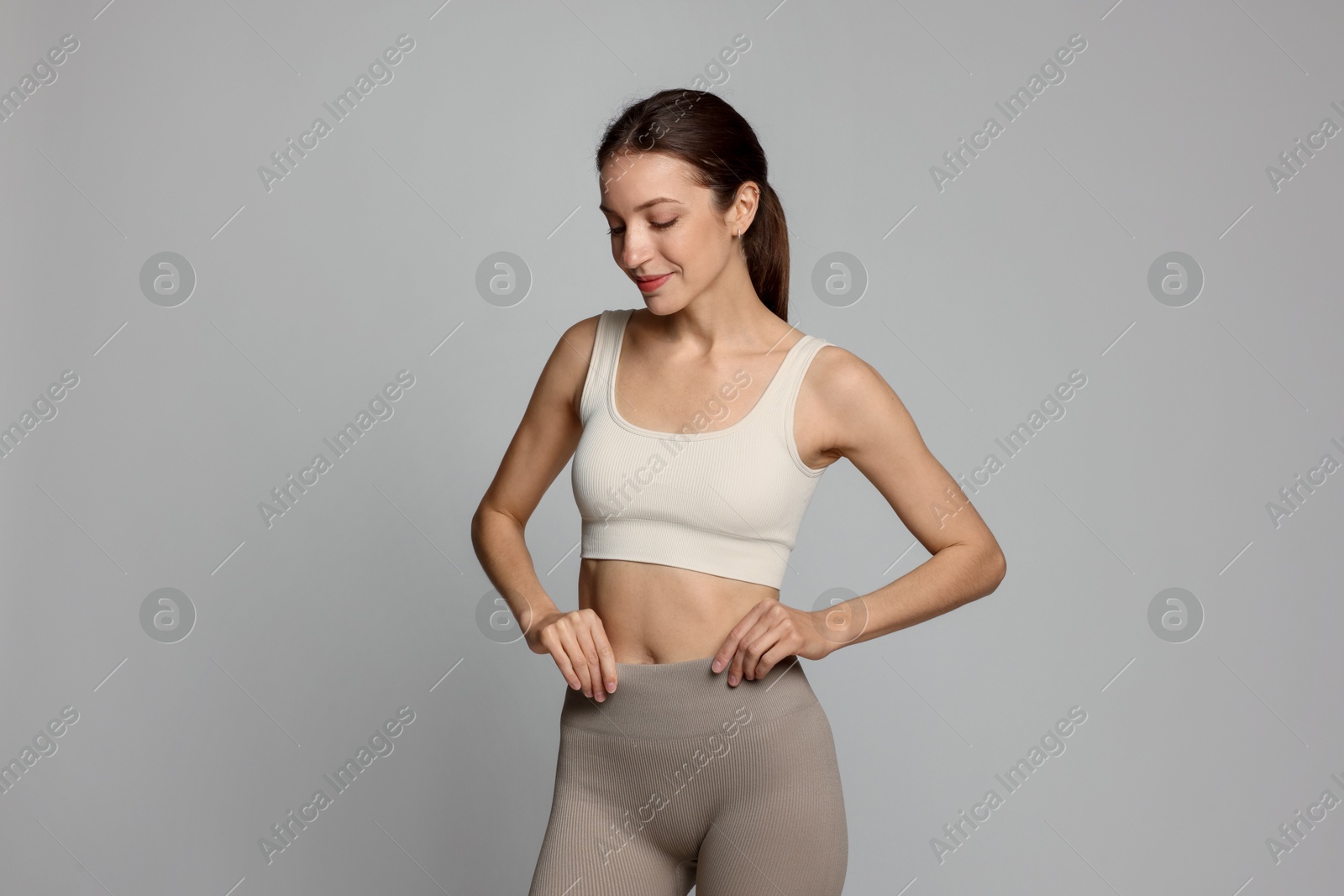 Beautiful woman with flat belly on gray background Photo of Beautiful woman with flat belly on gray background