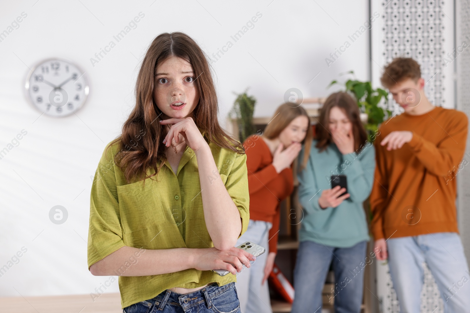 Teenage girl with smartphone suffering from bullying at school, selective focus Photo of Teenage girl with smartphone suffering from bullying at school, selective focus