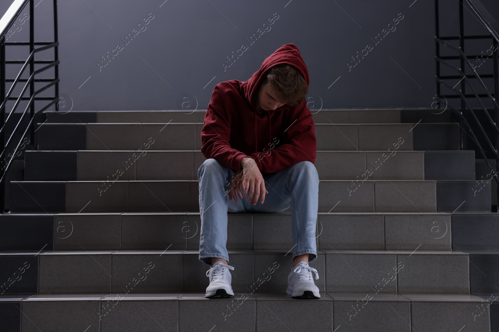 Bullying. Upset teenage boy on stairs indoors Photo of Bullying. Upset teenage boy on stairs indoors