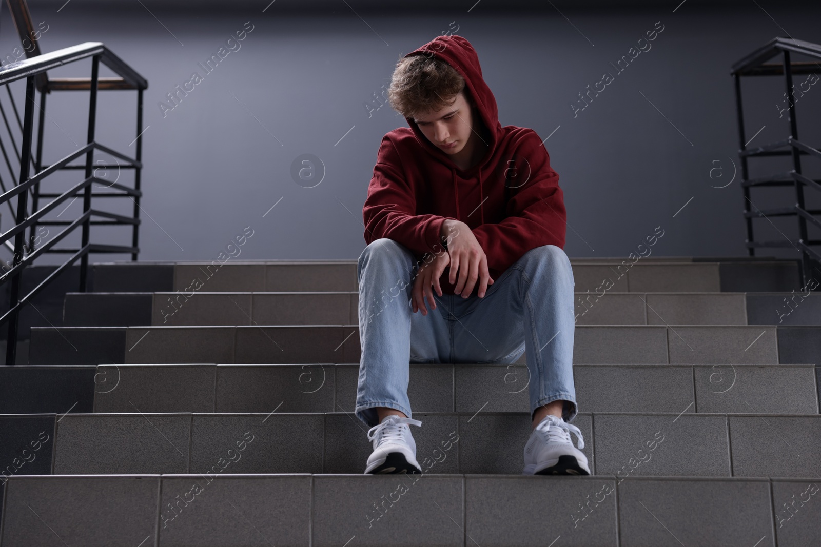 Bullying. Upset teenage boy on stairs indoors Photo of Bullying. Upset teenage boy on stairs indoors