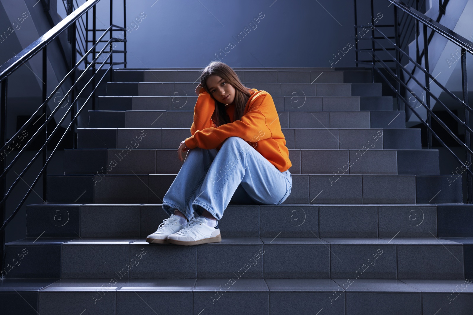 Bullying. Upset teenage girl on stairs indoors Photo of Bullying. Upset teenage girl on stairs indoors