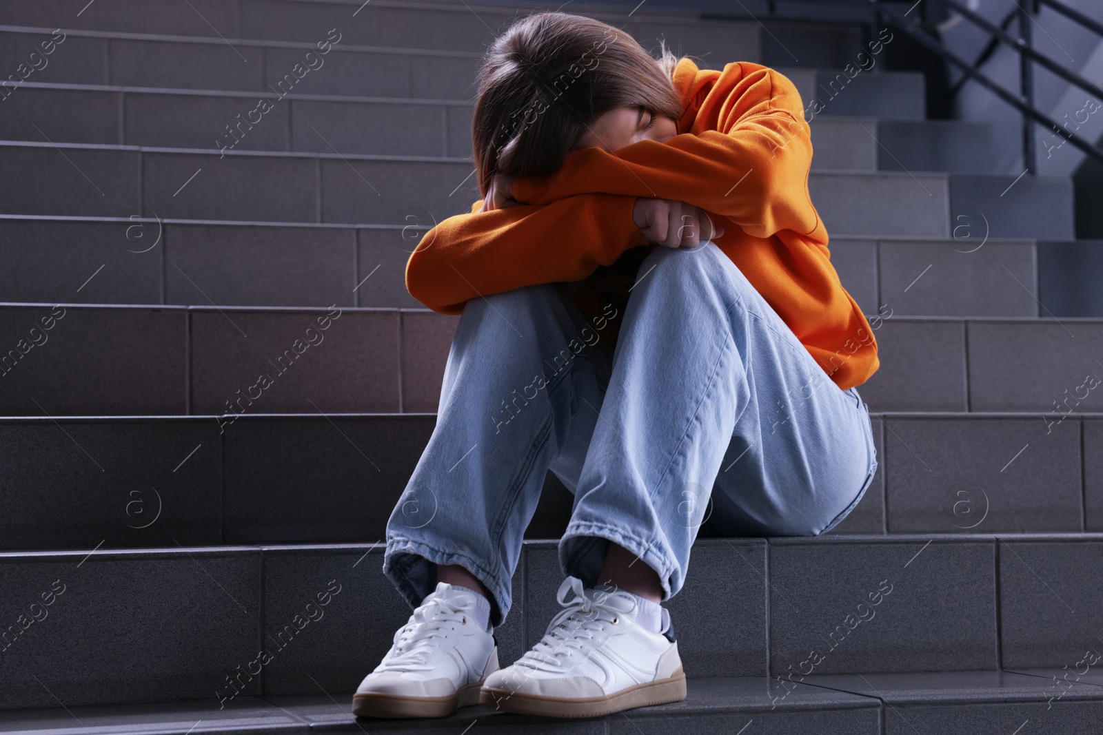 Bullying. Upset teenage girl on stairs indoors Photo of Bullying. Upset teenage girl on stairs indoors