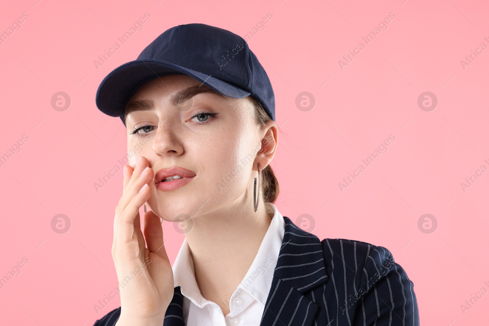 Portrait of beautiful woman in stylish baseball hat on pink background, closeup Photo of Portrait of beautiful woman in stylish baseball hat on pink background, closeup