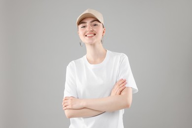Photo of Smiling woman in stylish baseball hat on grey background