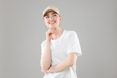Photo of Smiling woman in stylish baseball hat on grey background