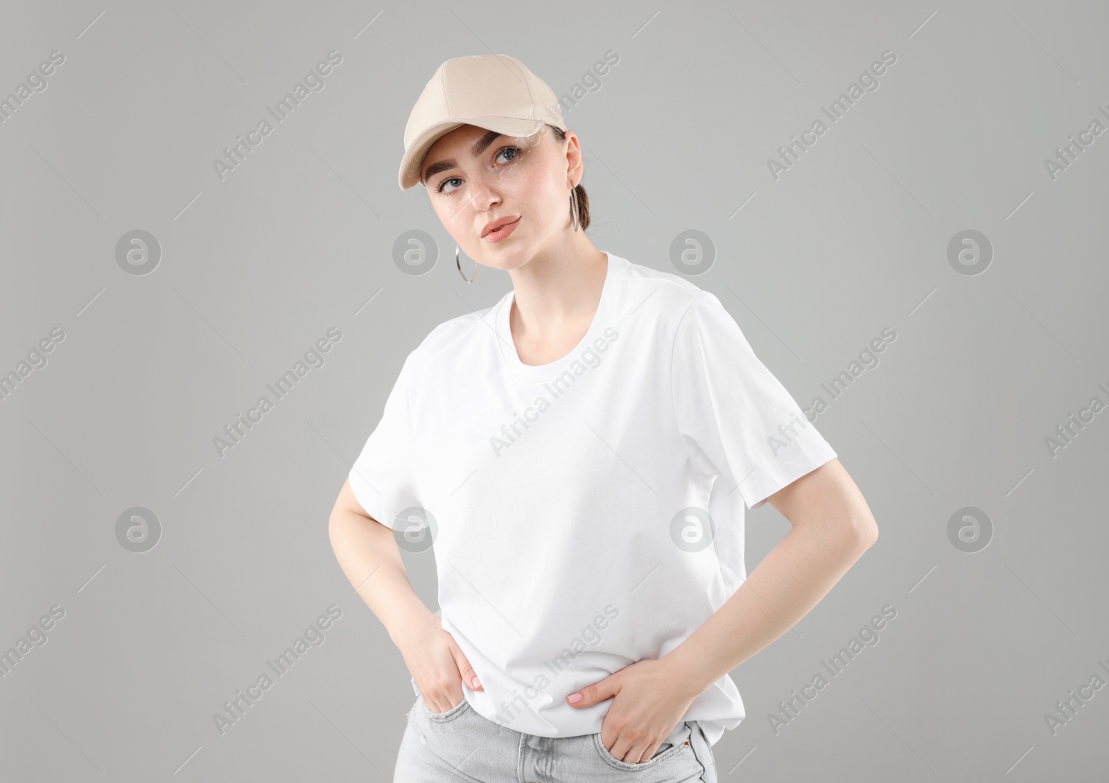 Beautiful woman in stylish baseball hat on grey background Photo of Beautiful woman in stylish baseball hat on grey background