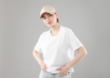 Photo of Beautiful woman in stylish baseball hat on grey background