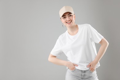 Photo of Portrait of smiling woman in stylish baseball hat on grey background. Space for text