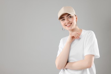 Photo of Portrait of smiling woman in stylish baseball hat on grey background. Space for text