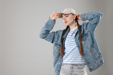 Photo of Beautiful woman in stylish baseball hat on grey background. Space for text