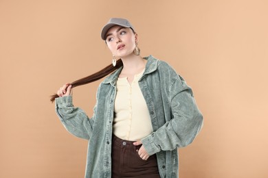 Photo of Beautiful woman in stylish baseball hat on beige background