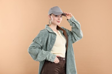 Photo of Portrait of beautiful woman in stylish baseball hat on beige background
