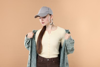 Photo of Beautiful woman in stylish baseball hat on beige background