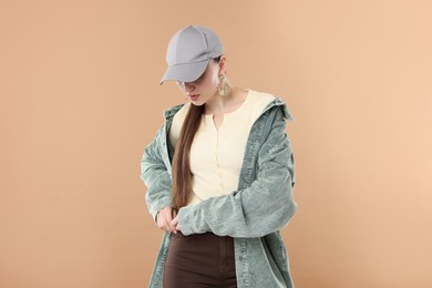 Photo of Beautiful woman in stylish baseball hat on beige background