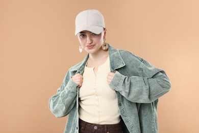 Photo of Portrait of beautiful woman in stylish baseball hat on beige background